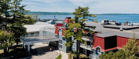 A multi-story building with a red roof, a covered parking area, and a view of a body of water.