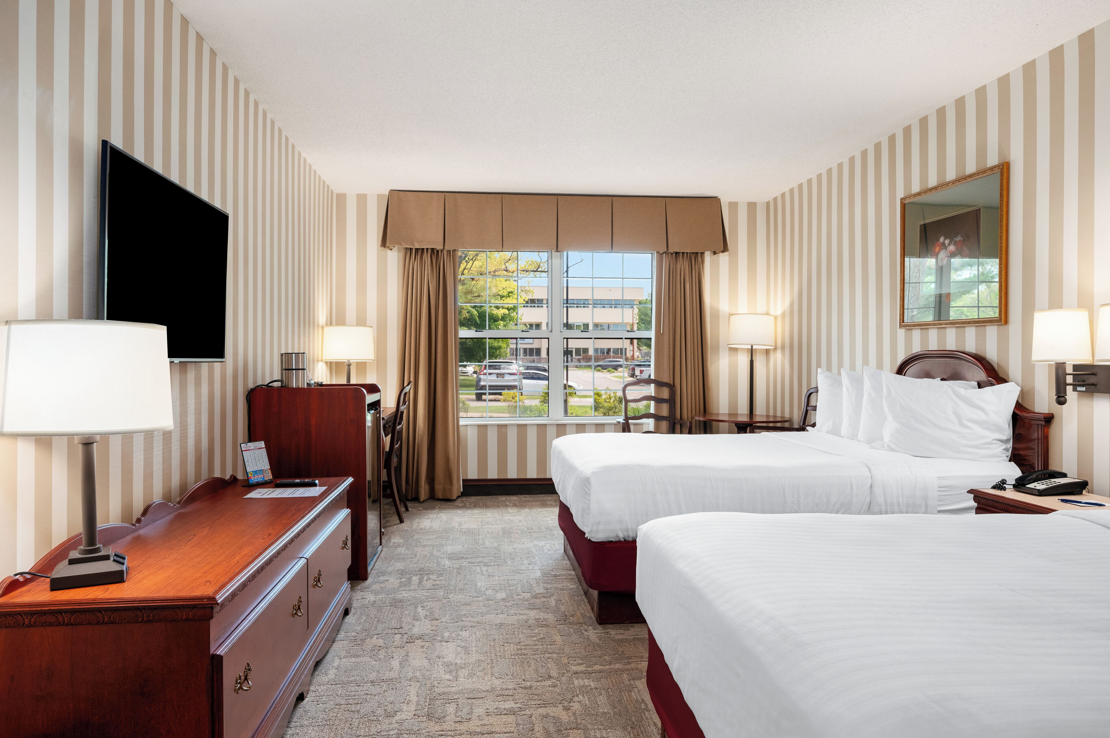 Een hotelkamer met twee bedden, een bureau, een televisie en een raam met uitzicht.