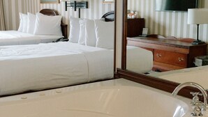 Ein Hotelzimmer mit einem großen Bett, einer Sitzecke mit Schreibtisch, einem Fernseher und einer Badewanne.
