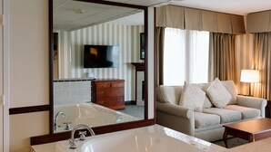 Ein Hotelzimmer mit einem großen Spiegel, einer Badewanne, einem Sofa und einem Fernseher.