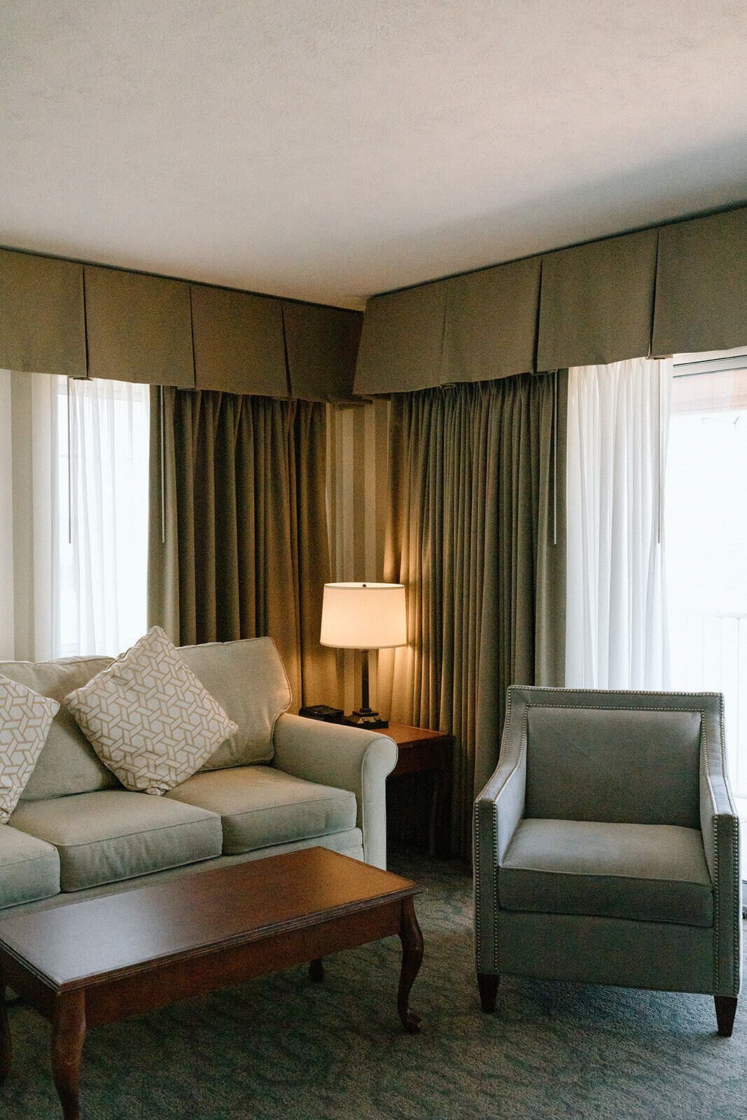 A hotel room with a sofa, armchair, and a small table.
