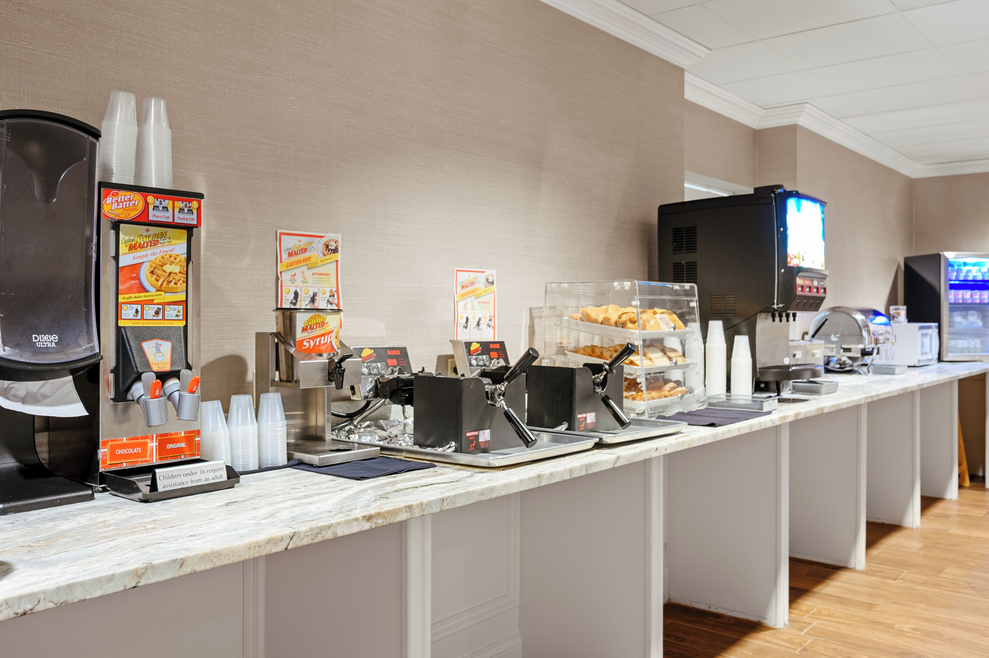 A self-service breakfast bar with various food options and beverage dispensers.