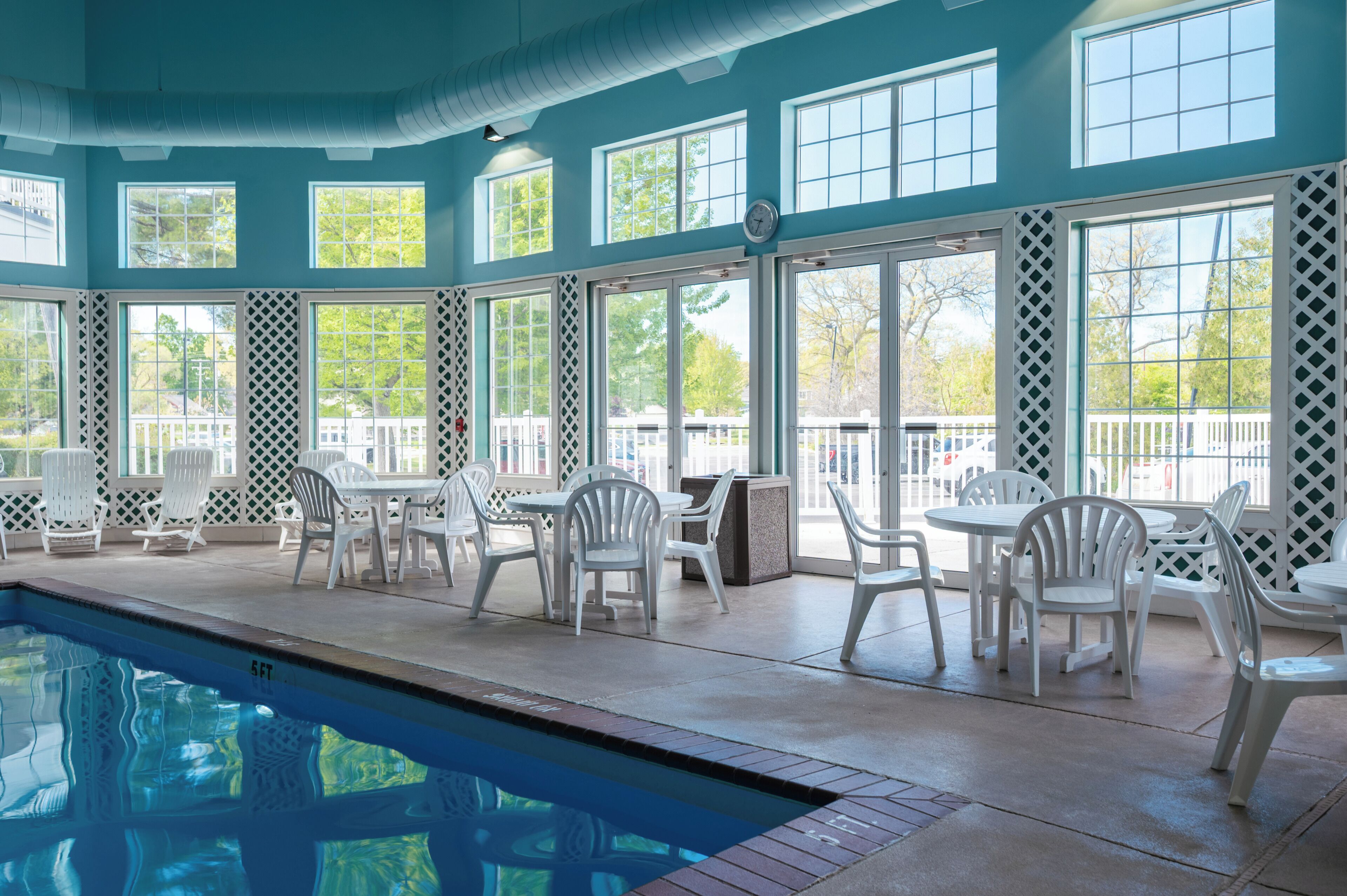 An indoor swimming pool area with multiple seating arrangements and large windows.