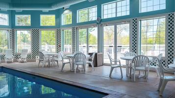 An indoor swimming pool area with multiple seating arrangements and large windows.
