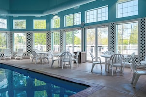 An indoor swimming pool area with multiple seating arrangements and large windows.