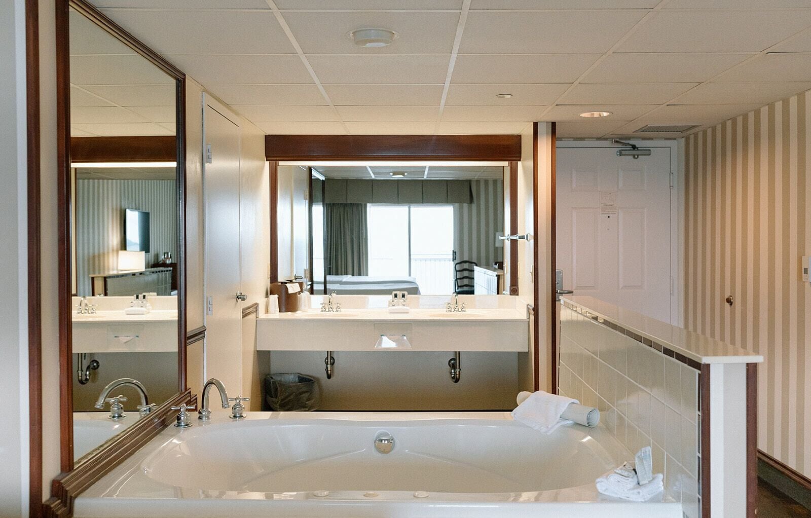 A hotel bathroom with a large bathtub, two sinks, and a mirror above the sink.