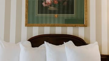 A neatly made bed with white pillows and a framed floral artwork above it.