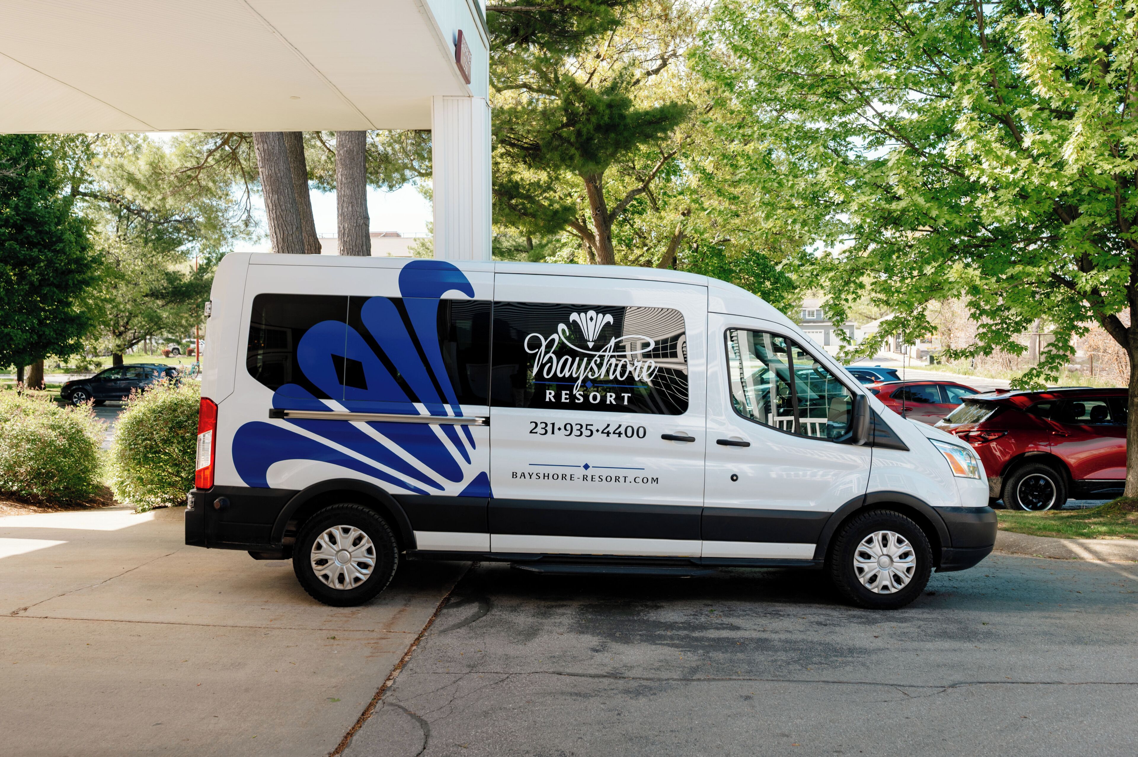 A white van with 'Bayshore Resort' branding parked in front of a building.