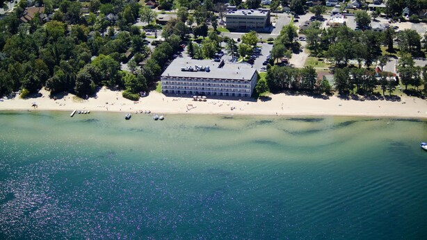 Eine Luftaufnahme einer Küstenregion mit einem großen Gebäude, einem Strand und einem Parkplatz.