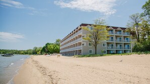 Ein Strandhotel mit mehreren Balkonen, einem Sandstrand und blauem Himmel.
