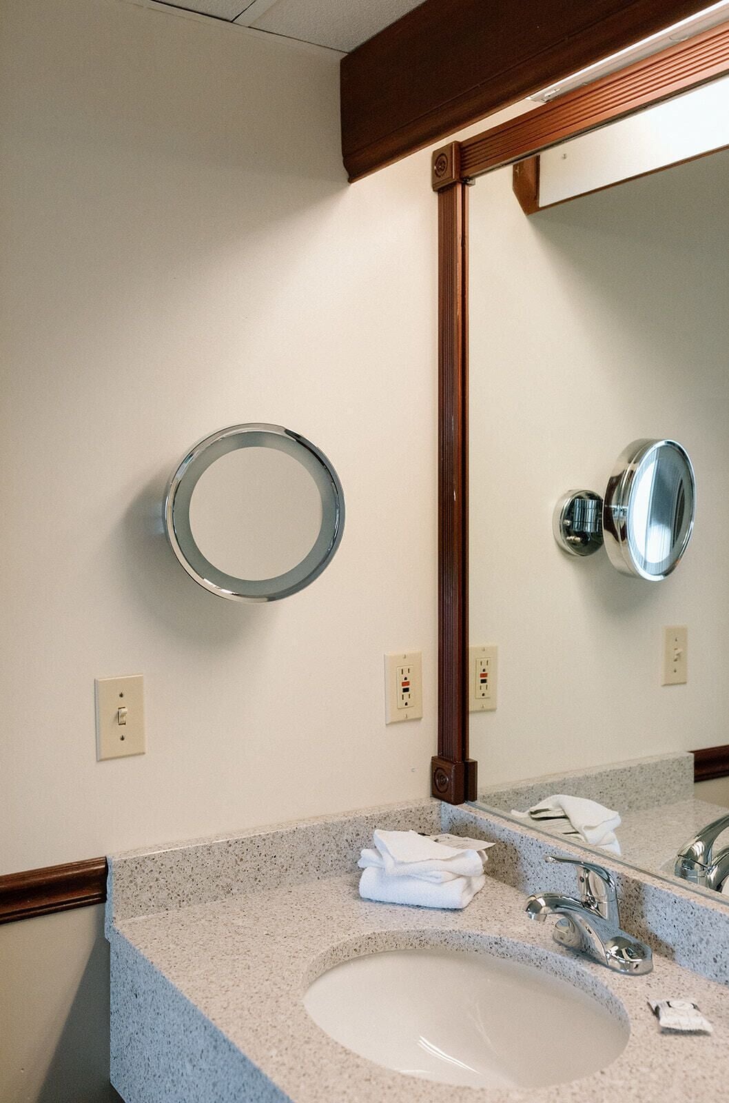 A bathroom with a granite countertop, a white sink, a mirror, and a towel rack.