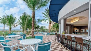 A rooftop bar with white tables and chairs, a checkered floor, and palm trees. - Residence Inn Fort Lauderdale Pompano Beach / Oceanfront (Pompano Beach)