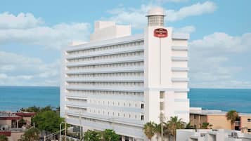 A white hotel with a Marriott logo, multiple floors, and a view of the ocean.