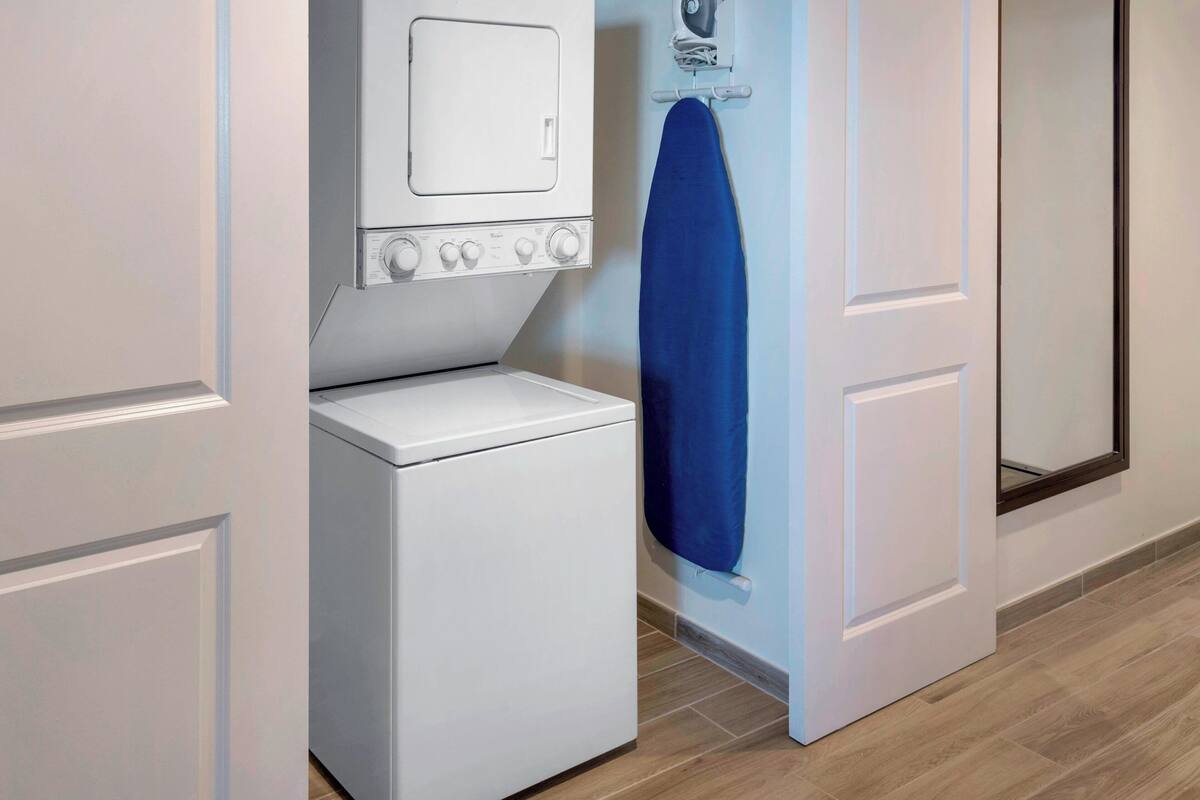 A laundry room with a washing machine, dryer, and ironing board.