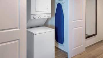 A laundry room with a washing machine, dryer, and ironing board.