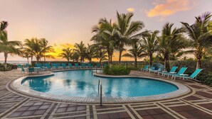 A pool area with lounge chairs and palm trees, surrounded by a patterned walkway. - Residence Inn Fort Lauderdale Pompano Beach / Oceanfront (Pompano Beach)