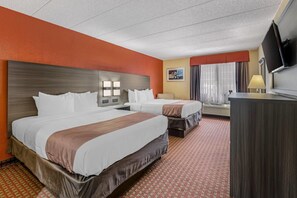 A hotel room with two beds, a desk, a TV, and a window with curtains. - Quality Inn & Suites Lincoln South (Lincoln)