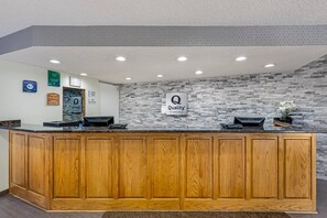 A reception desk with a stone wall backdrop, a sign for 'Quality by Choice Hotels,' and a '2015 Award for Quality' plaque. - Quality Inn & Suites Lincoln South (Lincoln)