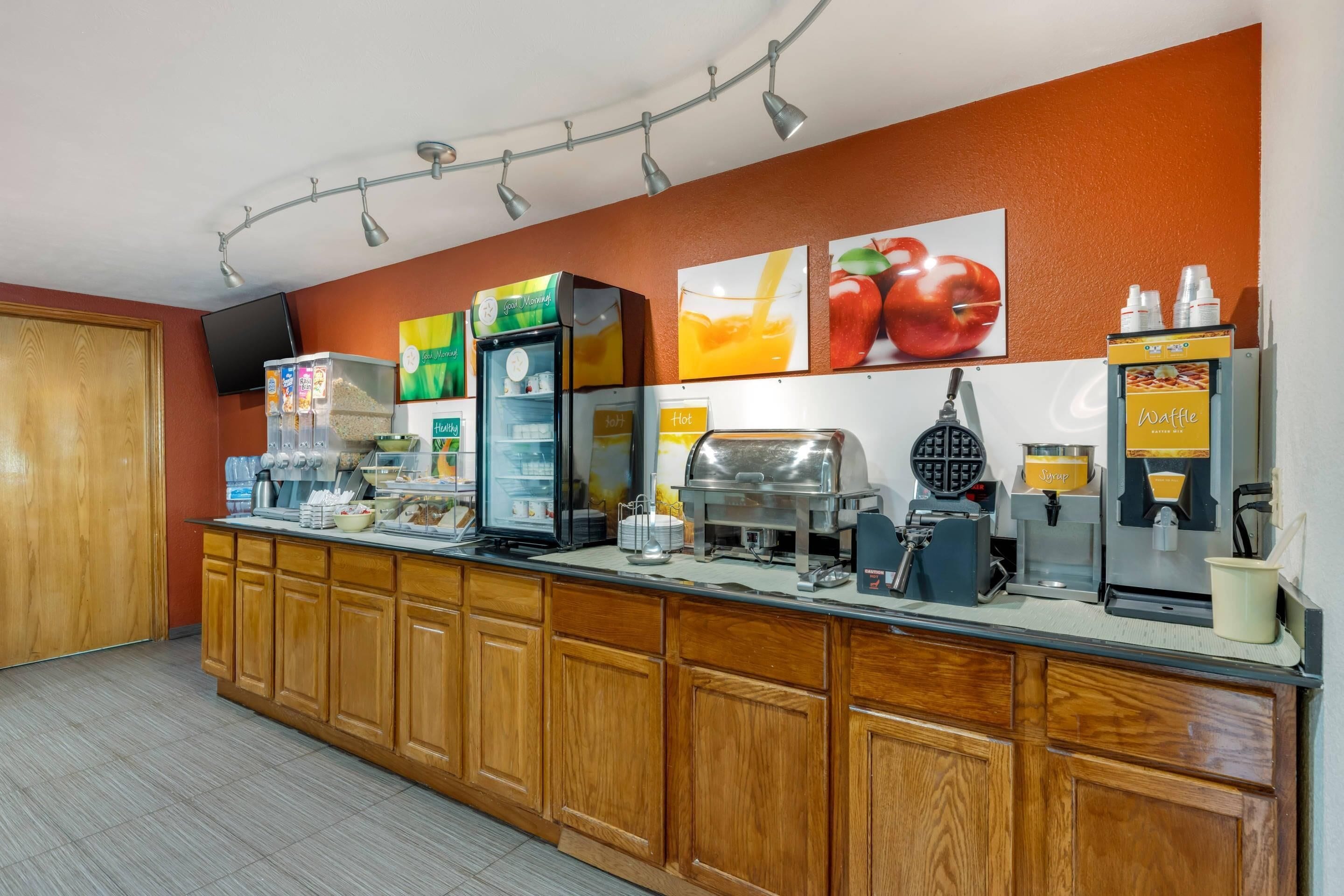 A breakfast bar with various food and drink dispensers, including a waffle maker and a coffee machine.