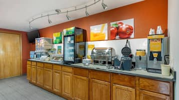 A breakfast bar with various food and drink dispensers, including a waffle maker and a coffee machine.