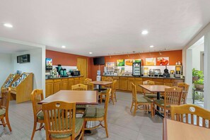 A restaurant with wooden furniture, a counter with food items, and a television. - Quality Inn & Suites Lincoln South (Lincoln)