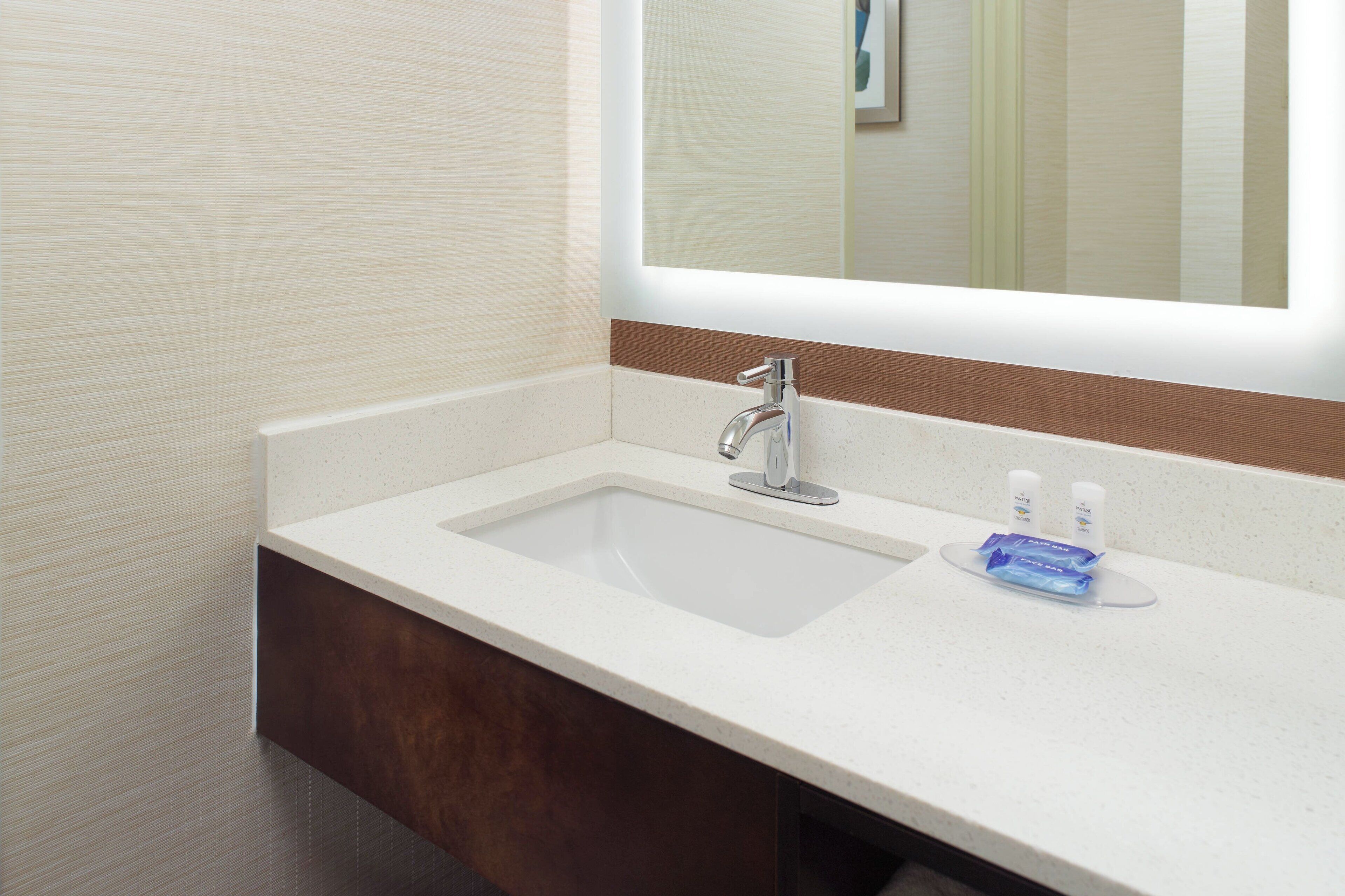 A bathroom with a white sink, a mirror, and two toiletries.