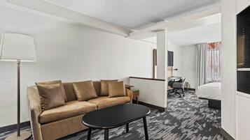 Habitación de hotel con sofá, una mesita, lámpara, escritorio con silla y cama.