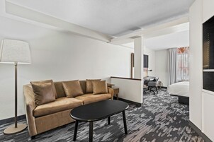 Habitación de hotel con sofá, una mesita, lámpara, escritorio con silla y cama.