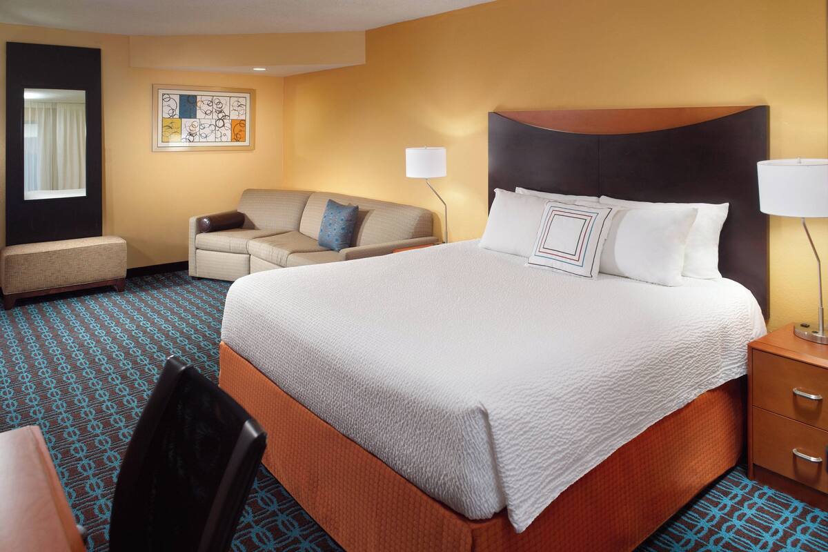 Una habitación de hotel con una cama grande, un sofá, un escritorio y una silla.