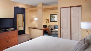 Una habitación de hotel con cama, televisión, escritorio, silla y lámpara.