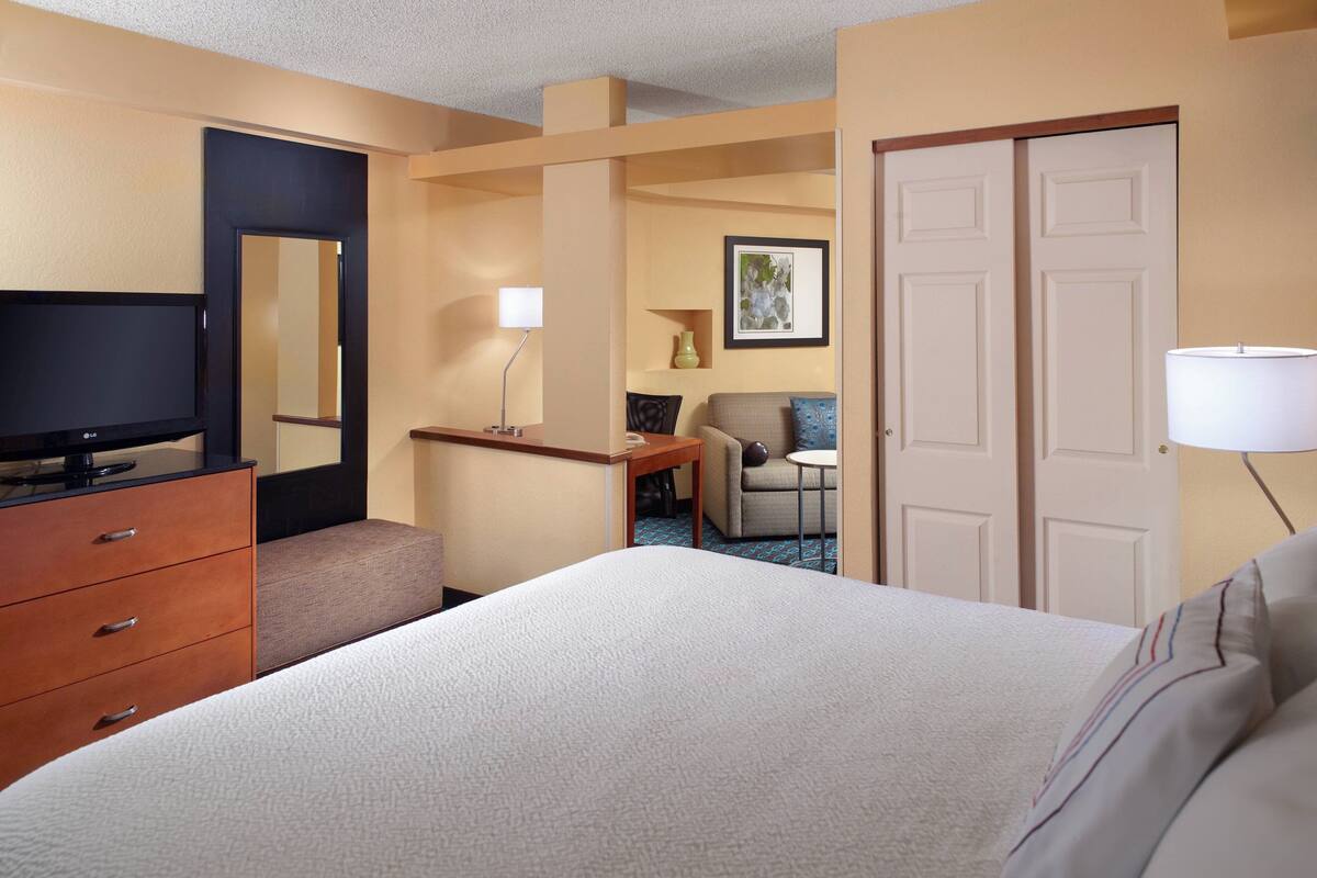 Una habitación de hotel con cama, televisión, escritorio, silla y lámpara.