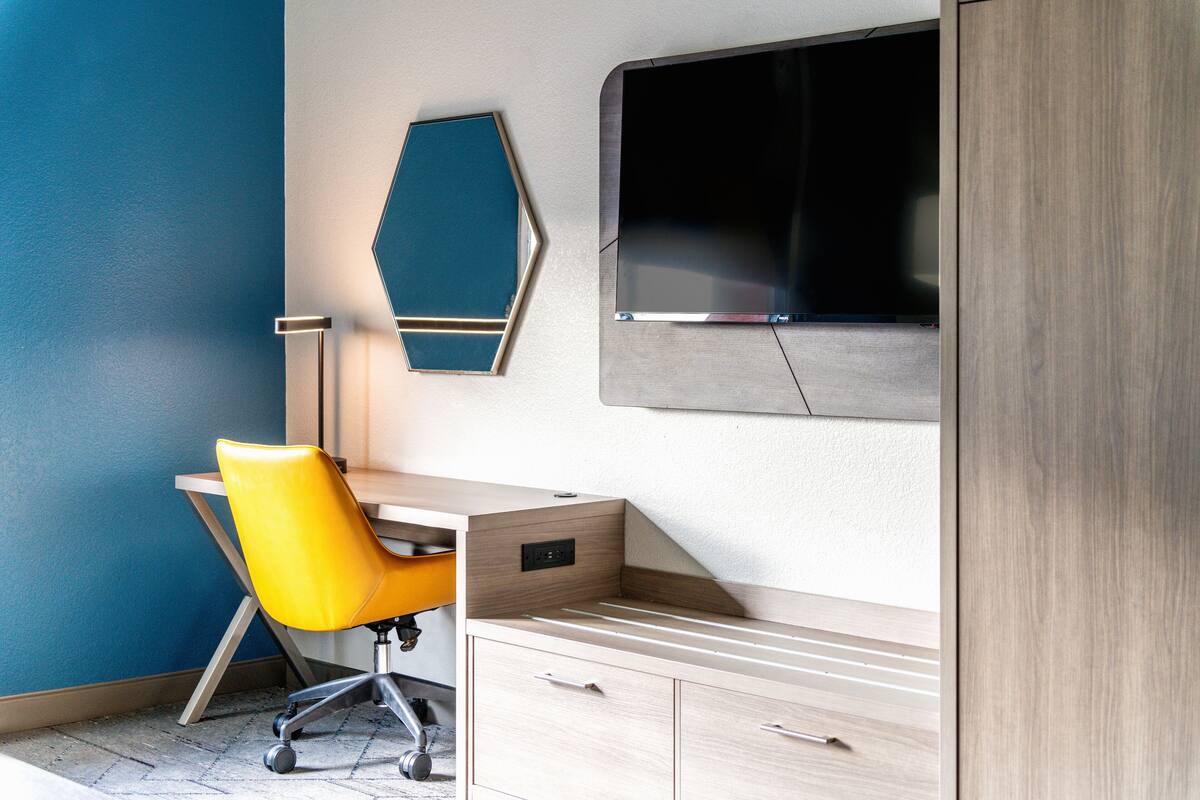 Un espacio de oficina moderno con un escritorio, una silla y un televisor montado.
