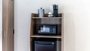 Eine kompakte Küchenzeile mit Mikrowelle, Kaffeemaschine und kleinem Kühlschrank.