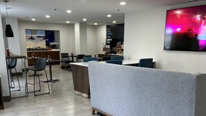 Eine moderne Hotellobby mit Empfangstresen, Sitzgelegenheiten und einer Kaffeestation.