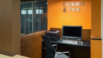 Un petit bureau équipé d’un ordinateur, d’une imprimante et d’une pancarte indiquant : « Se connecter et imprimer ».