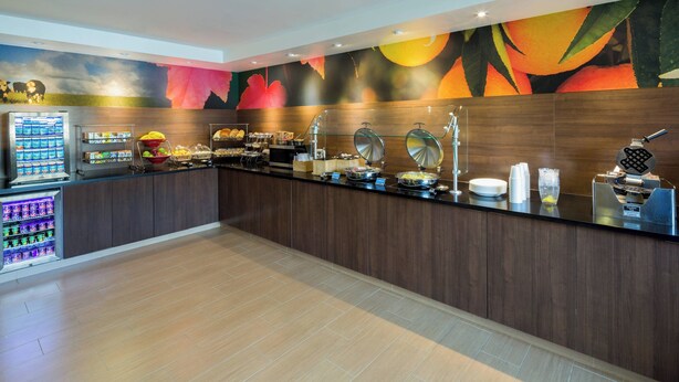 A buffet area with a variety of food options, a beverage dispenser, and a fruit bowl. - Fairfield Inn & Suites San Antonio Airport/North Star Mall (San Antonio)