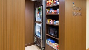 A corner with a vending machine stocked with snacks and beverages, a microwave, and a shelf with packaged goods. - Fairfield Inn & Suites San Antonio Airport/North Star Mall (San Antonio)