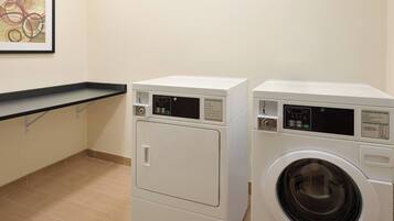 A laundry room with two front-loading washing machines and a black countertop.