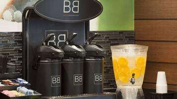 A beverage station with three dispensers labeled 'BB' and a large pitcher with orange slices.