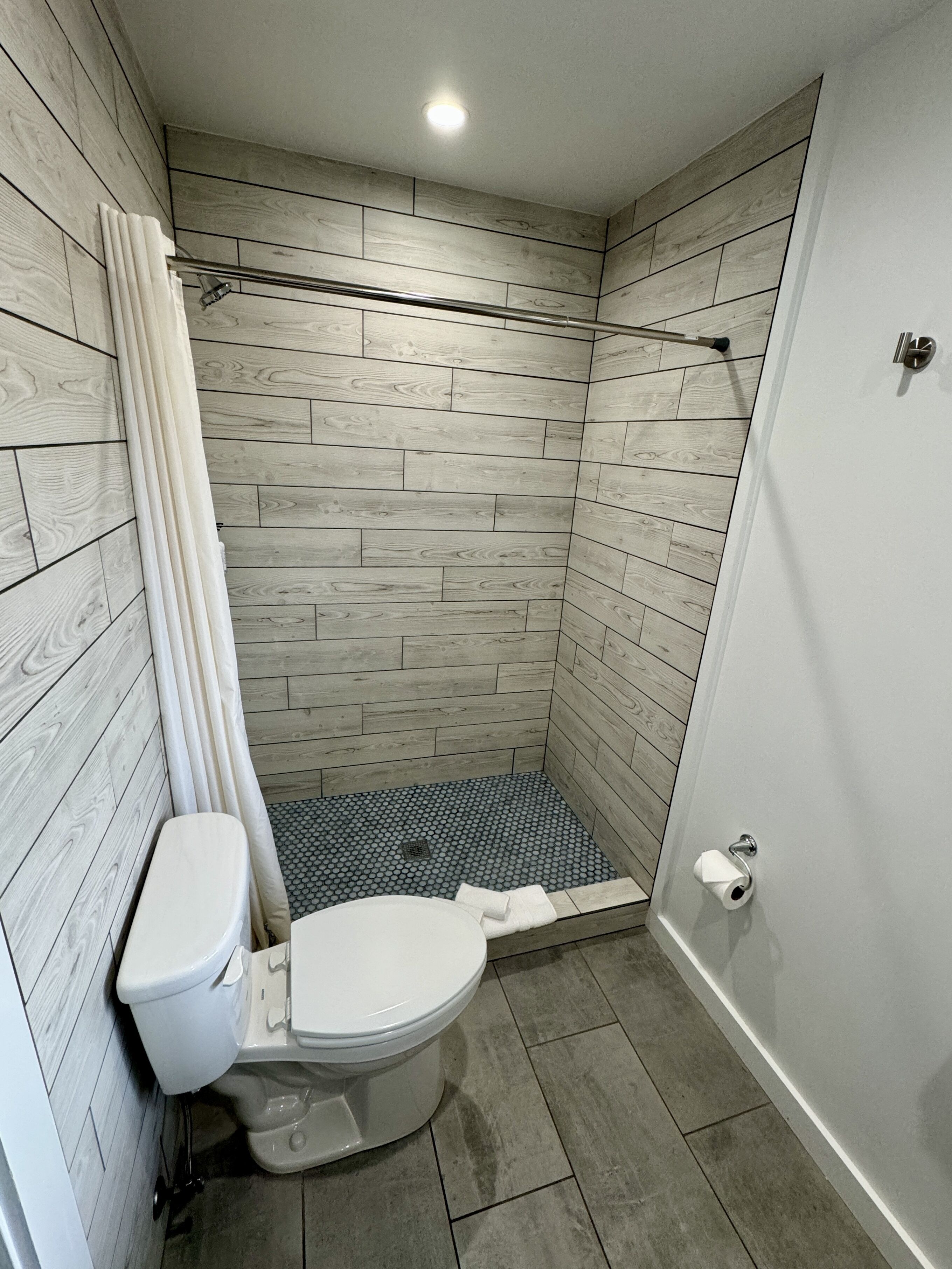 A small, modern bathroom with a shower, toilet, and a bathtub.