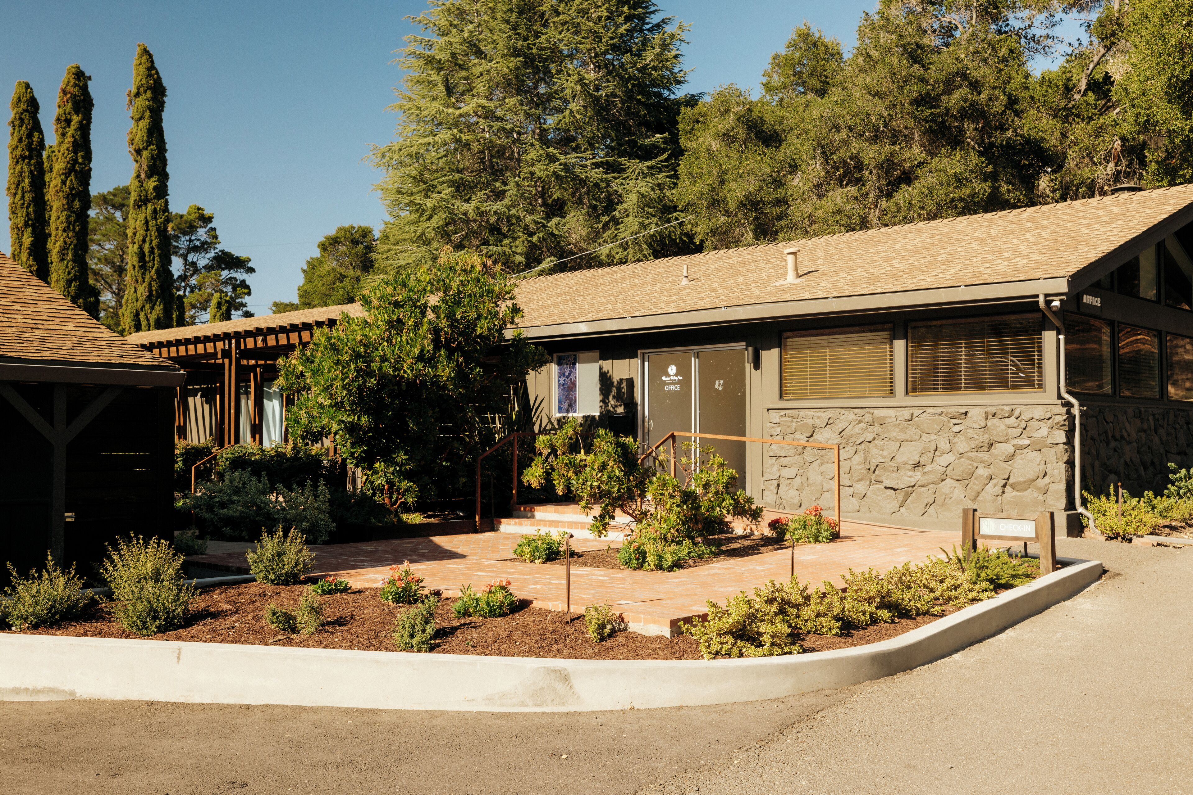 A building with a stone facade, a covered porch, and a landscaped garden area.