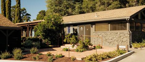 A building with a stone facade, a covered porch, and a landscaped garden area.