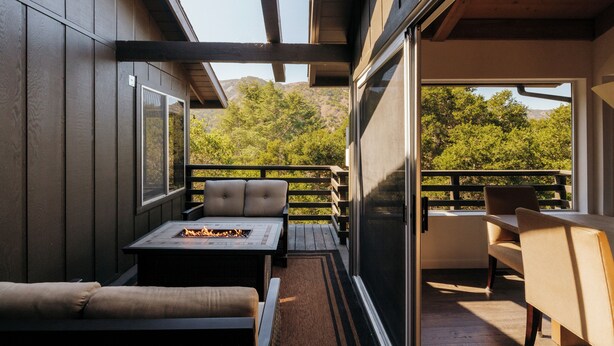 An outdoor deck with a fire pit, seating, and a view of the surrounding landscape. - Hidden Valley Inn (Carmel Valley)