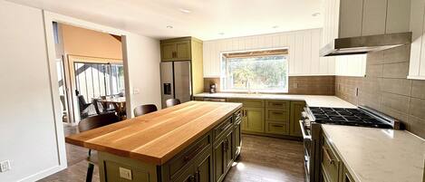 A modern kitchen with wooden countertops, green cabinets, and a large island.