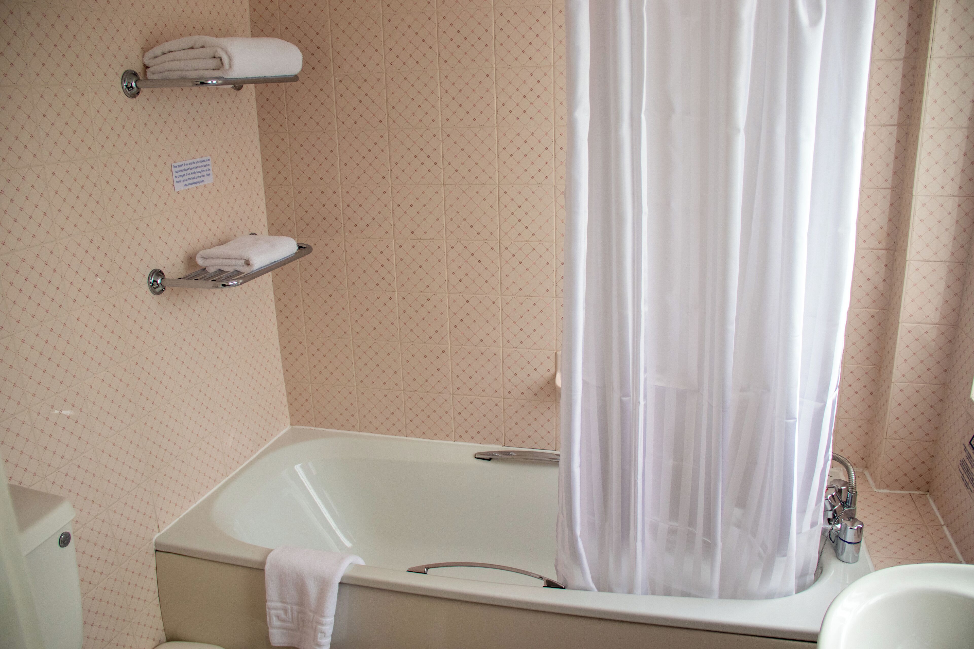 A bathroom with a bathtub, a shower curtain, and a towel rack.