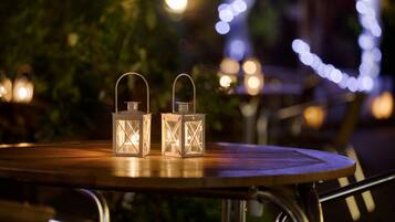 Deux lanternes allumées sur une table en bois, à l’extérieur, pendant la nuit.