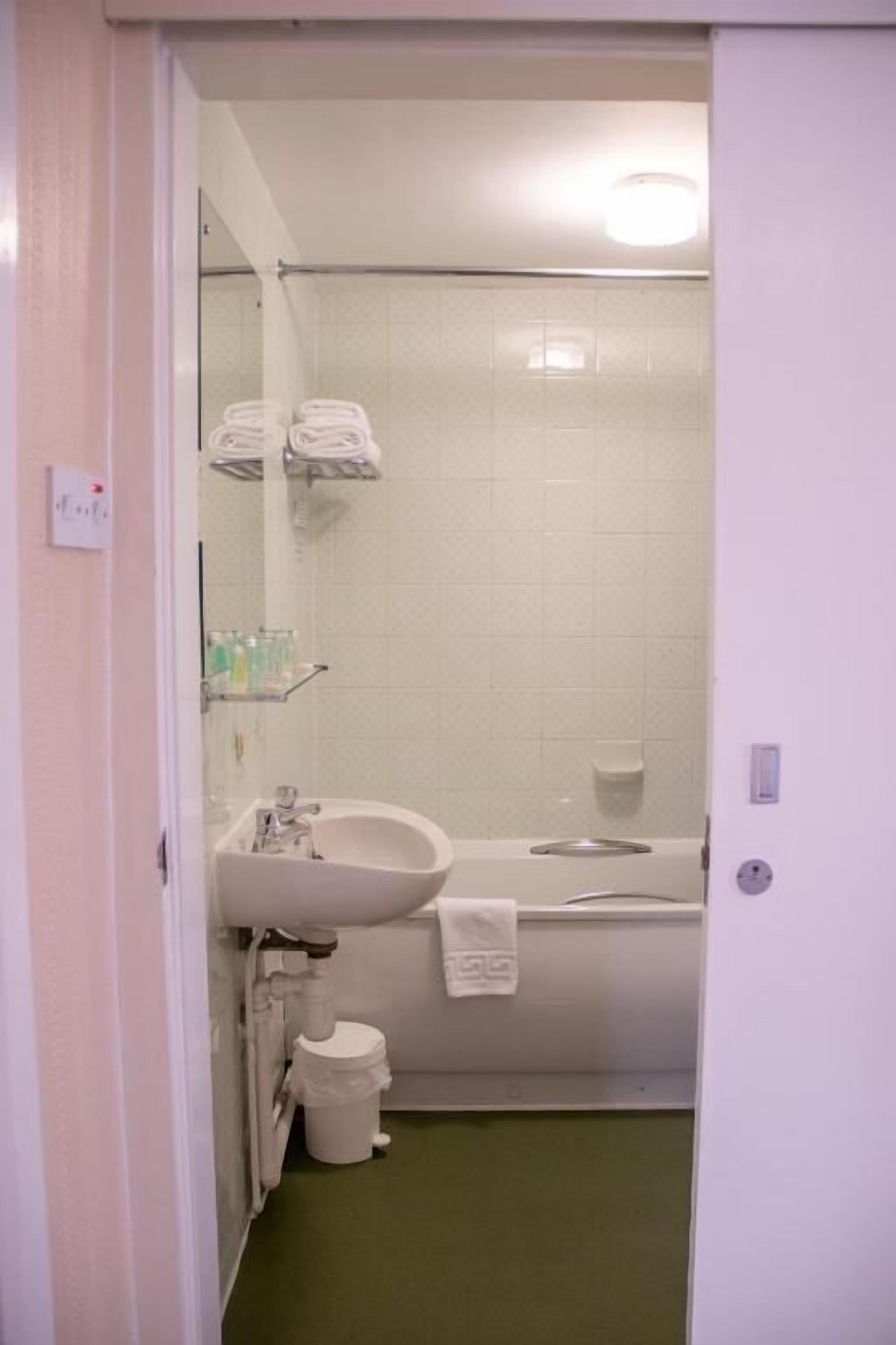 A bathroom with a sink, mirror, towel rack, and a shower area.