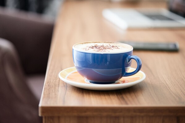 Una taza azul de café sobre un plato blanco sobre una mesa de madera.