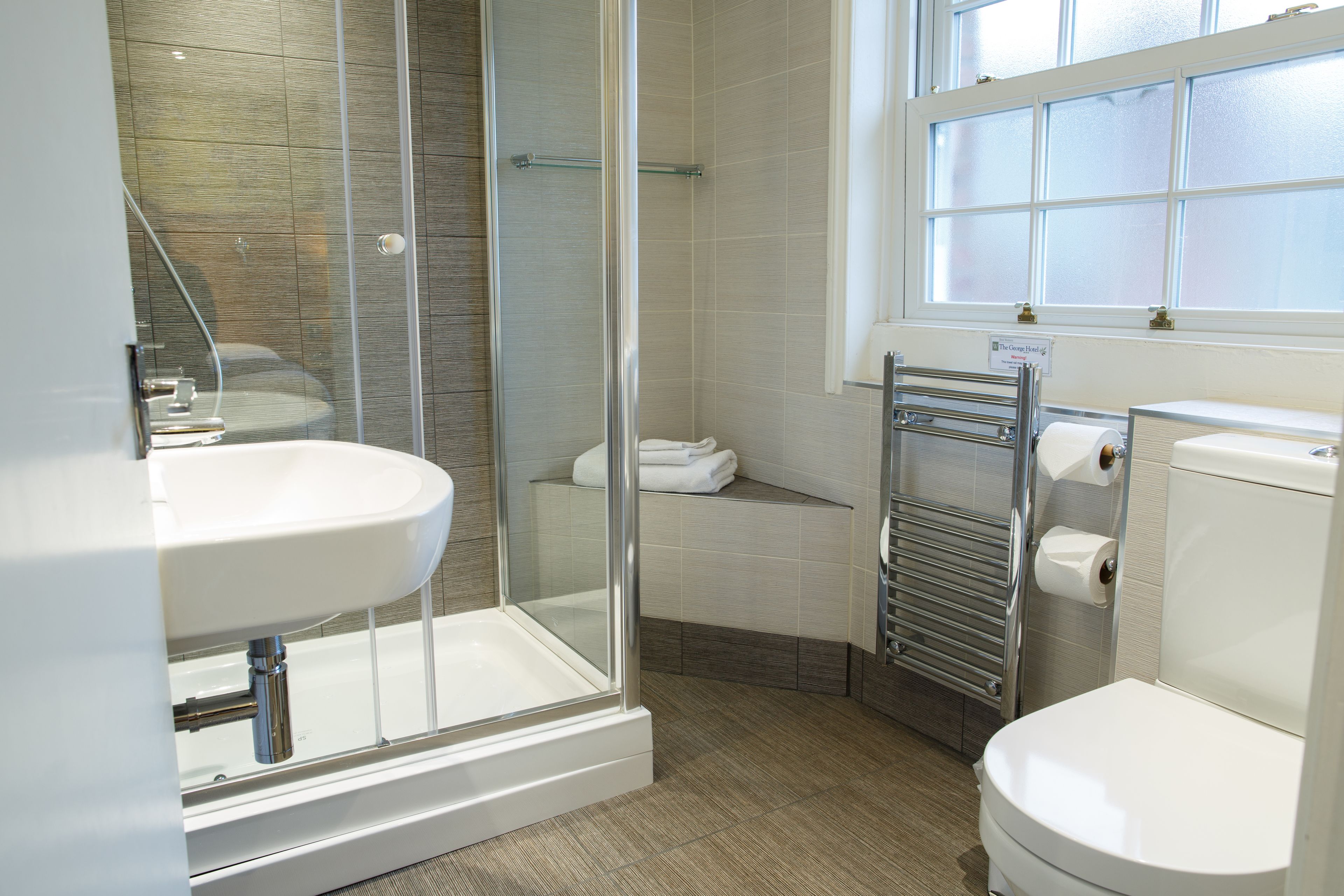 A modern bathroom with a glass-enclosed shower, a white sink, and a toilet.