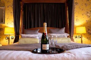 A bottle of Moët & Chandon champagne on a tray with two glasses on a bed in a room with a canopy bed and curtains. - Best Western Lichfield City Centre The George Hotel (Lichfield)